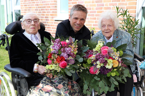 Pflegedienstleiter André Kreft überreichte Käthe Iken (links) und Gisela Brinkmann (rechts) zu ihren Geburtstagen bunte Frühlingssträuße. Foto: Diakonie