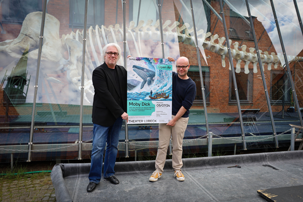 Axel Wuttke (Vorstandsvorsitzender der Gesellschaft der Theaterfreunde Lübeck e. V.) und Malte C. Lachmann (Schauspieldirektor am Theater Lübeck gGmbH) halten das Veranstaltungsplakat hoch. Foto: Sebastian Brummer