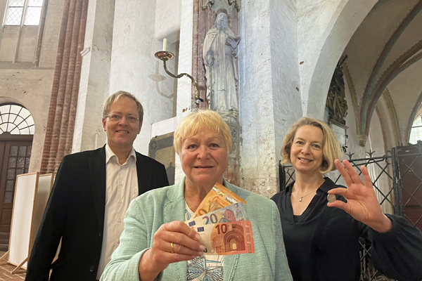 Jeder Euro zählt! Die Lübecker Geschäftsfrau Ellen Ehrich (Mitte) mit Marienpastor Robert Pfeifer (links) und Kirsten Müller-Klatz aus dem Kirchengemeinderat (rechts) vor der Skulptur des Heiligen Antonius in St. Marien. Foto: Annkathrin Bornholdt