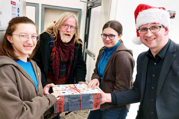 Geschenke gehörten auch zur Weihnachtsfeier: Frederike Schmähl (links) und Katharina Esse vom MOO-Projekt überreichen mit Beratungsstellen-Mitarbeiter Alex Krahl (rechts) ein Geschenk an Christof Schlüter. Foto: Hendrik Mulert